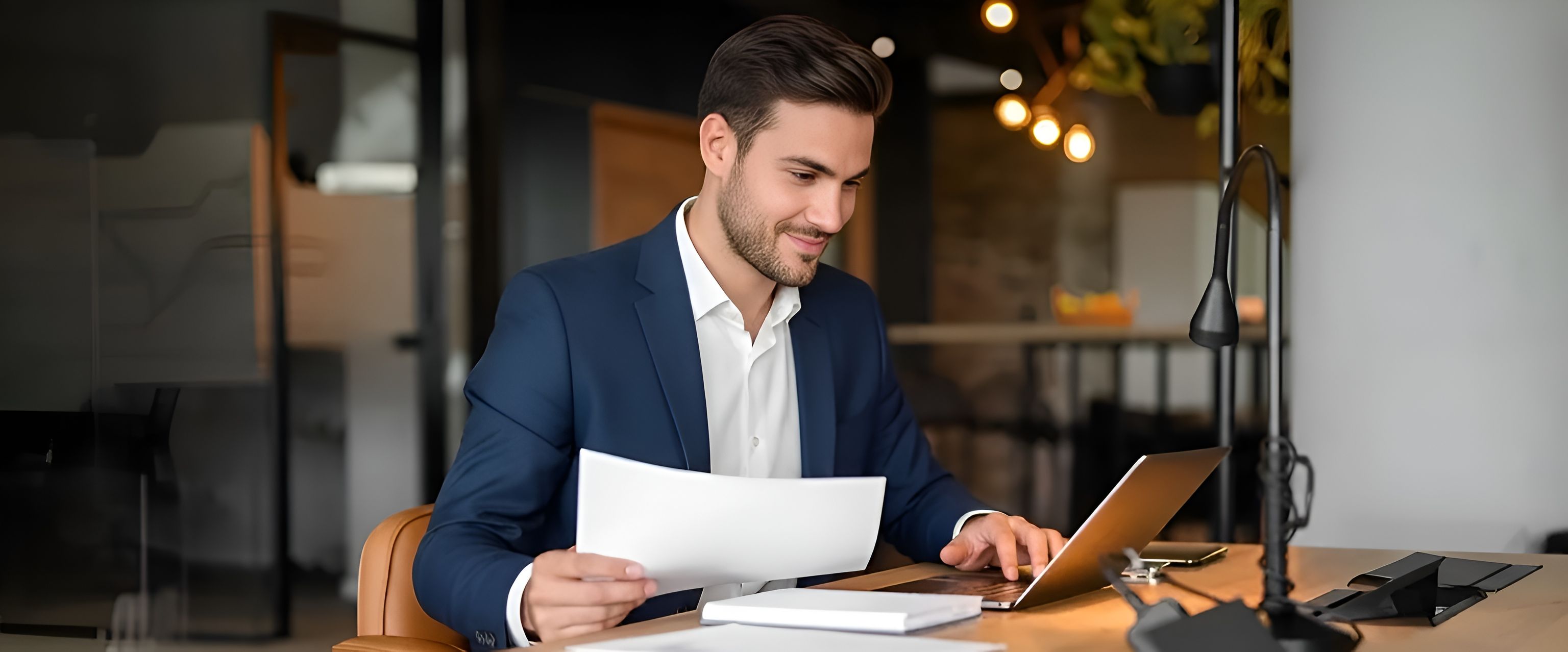 M&A professional reviewing documents at a laptop
